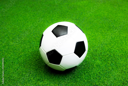 Soccer ball black and white leather on the green artificial grass field for sport background.