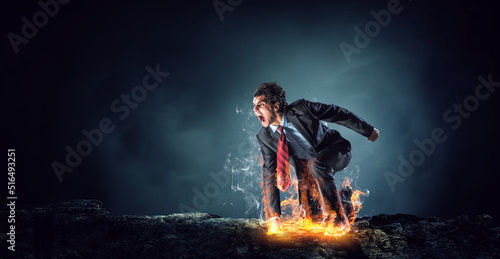 Determined businessman leaving fire trails on asphalt © Sergey Nivens