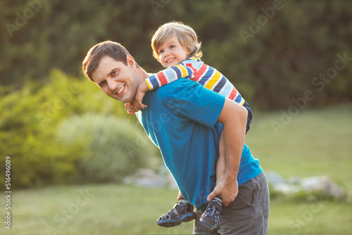 Casual active father and happy little son walking playing in the park on vacation on a sunny summer day