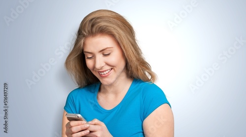 People and technology concept. Smiling girl using smartphone, texting on mobile phone
