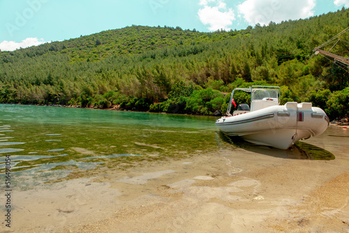 Beautiful view Bodrum Türkbükü bay.Boat docked on the beach.Green forest and clear sky.