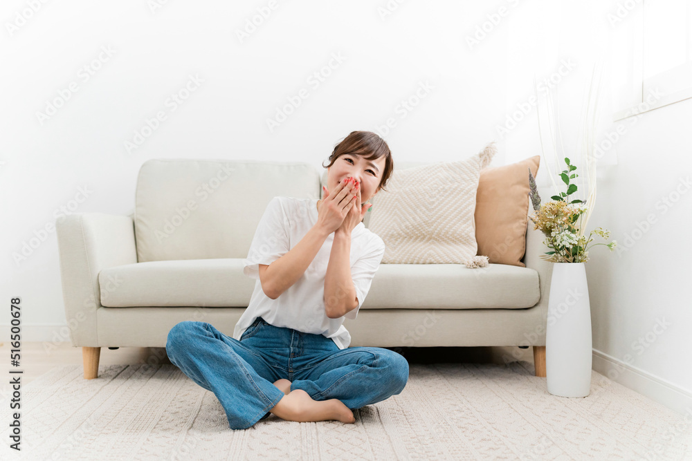 家のカーペットでリラックスするデニム姿の日本人女性（爆笑・笑顔）
