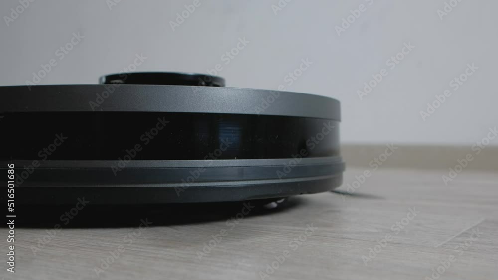 Robot vacuum cleaner vacuuming the floor in living room. Smart home with automated devices that simplify life. A smart vacuum cleaner cleans the floor. Robot vacuum cleaner vacuuming the floor in living room. Smart home with automated devices that simplify life. A smart vacuum cleaner cleans the floor.