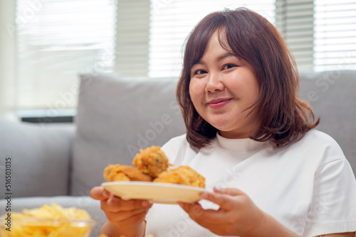 Chubby Asian woman express happiness When eating fried chicken, fries, and potato snacks