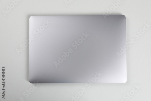 Blank close laptop on white table, top view