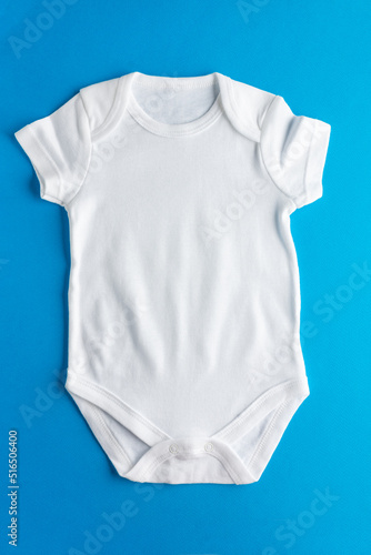 Flat lay mockup of white bodysuit for little kids on blue background for boys. Layout for the design and placement of logos, advertising. Close-up.