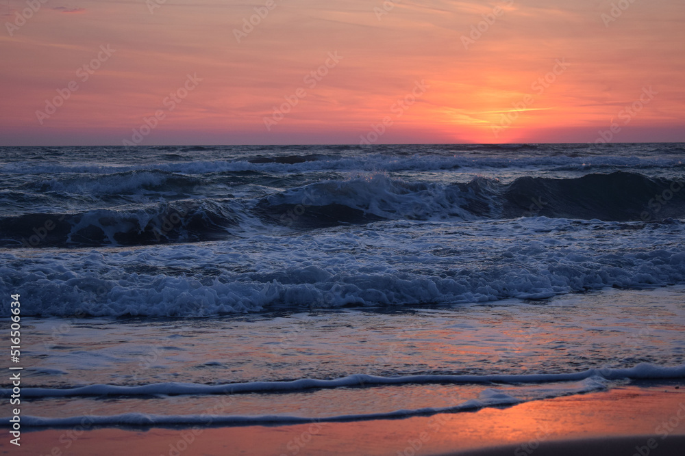 Obraz premium A beautiful sunset on the beach in the turbulent ocean