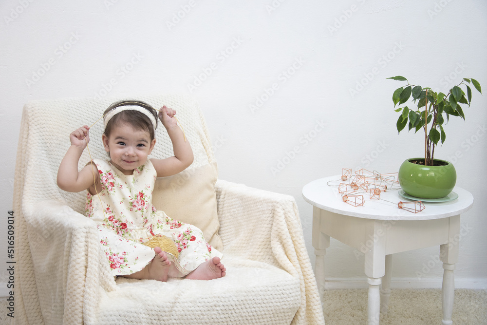 A girl is sitting against the background of a white wall dressed in twigs A girl is sitting against the background of a white wall dressed in twigs