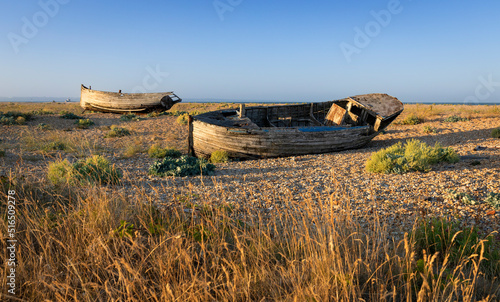 Old wrecked fishing boats on the shingle of Dungeness beach on the Kent coast south east England photo