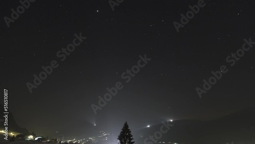 Time lapse shot of mountains Walmendinger Horn und Hohen Ifen seen from Rietzlern at night. The lights of villages and snowcats on the mountains are visible photo