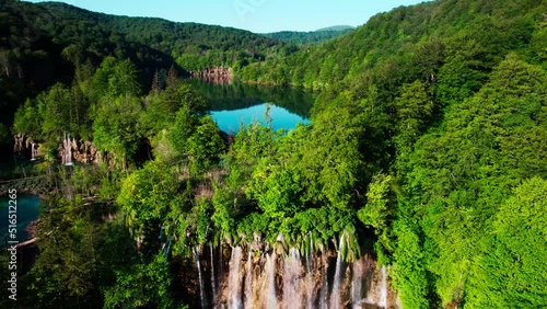 Set of waterfalls flowing from big dark water lake surrounded by green forest in Croatia photo