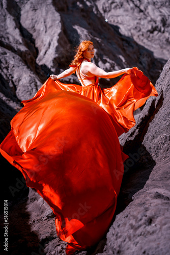 a girl in a red dress stands against the backdrop of a clay mountain © Антонина Лунева