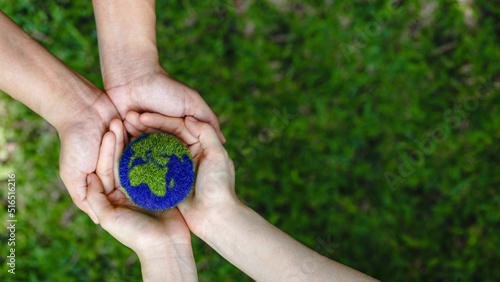 Many hands person holding the earth on a green background to protect nature Save and care World for sustainable. concept of the environment ecology and Earth Day