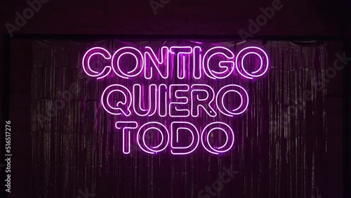 Pink neon glowing light on a wall with words ''Contigo quiero todo'' photo