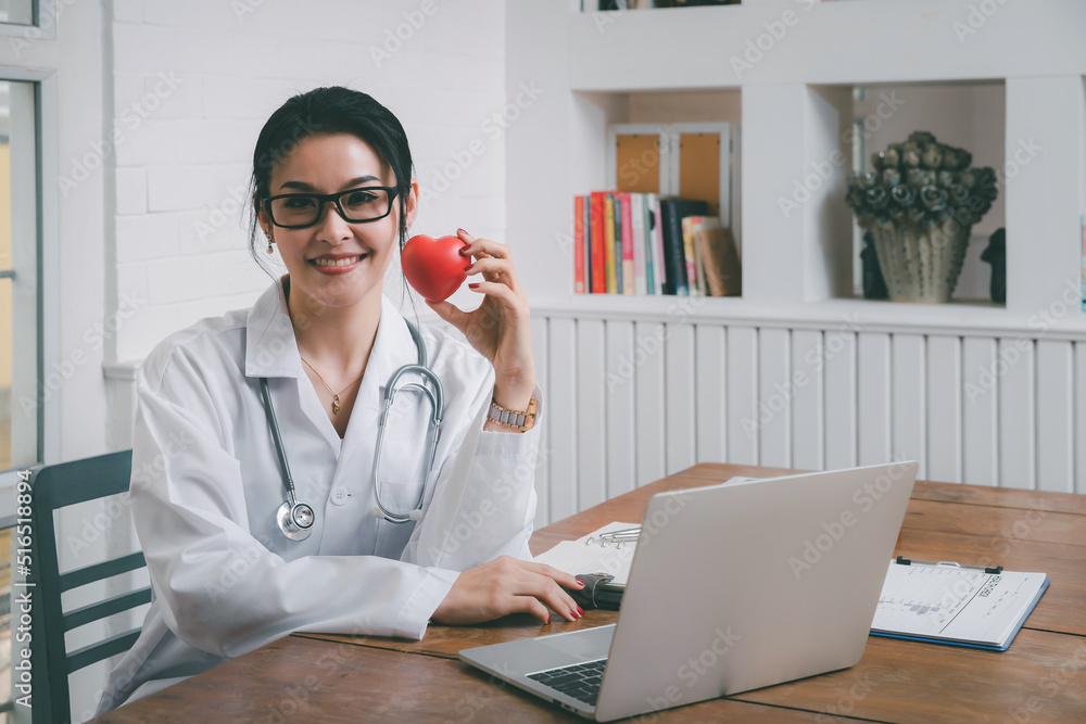 Female doctor holding a red heart ball in the hospital. Concept of health care and medical. Female doctor holding a red heart ball in the hospital. Concept of health care and medical.