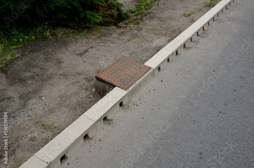 drainage hidden on the edge of an asphalt road Drainage system hidden in a perforated concrete gray curb. the water along the entire length of the road drains into the sewer through holes