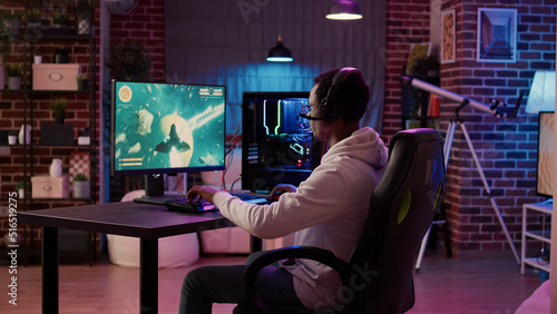 Photos African american man playing fast paced multiplayer space shooter using pc gaming setup having a good time in home living room