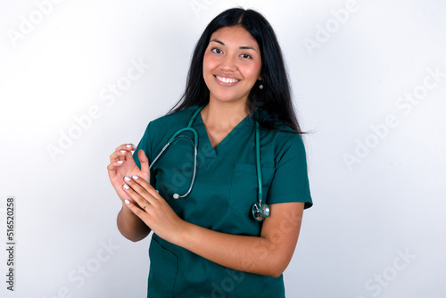 Doctor hispanic woman wearing surgeon uniform over white wall clapping and applauding happy and joyful, smiling proud hands together.