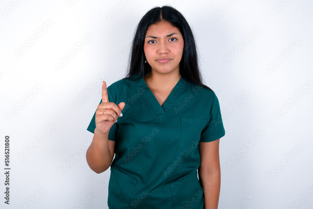 Doctor hispanic woman wearing surgeon uniform over white background frustrated and pointing to the front Doctor hispanic woman wearing surgeon uniform over white background frustrated and pointing to the front