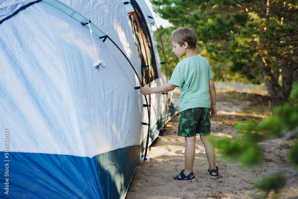 cute little caucasian boy helping to put up a tent. Family camping concept