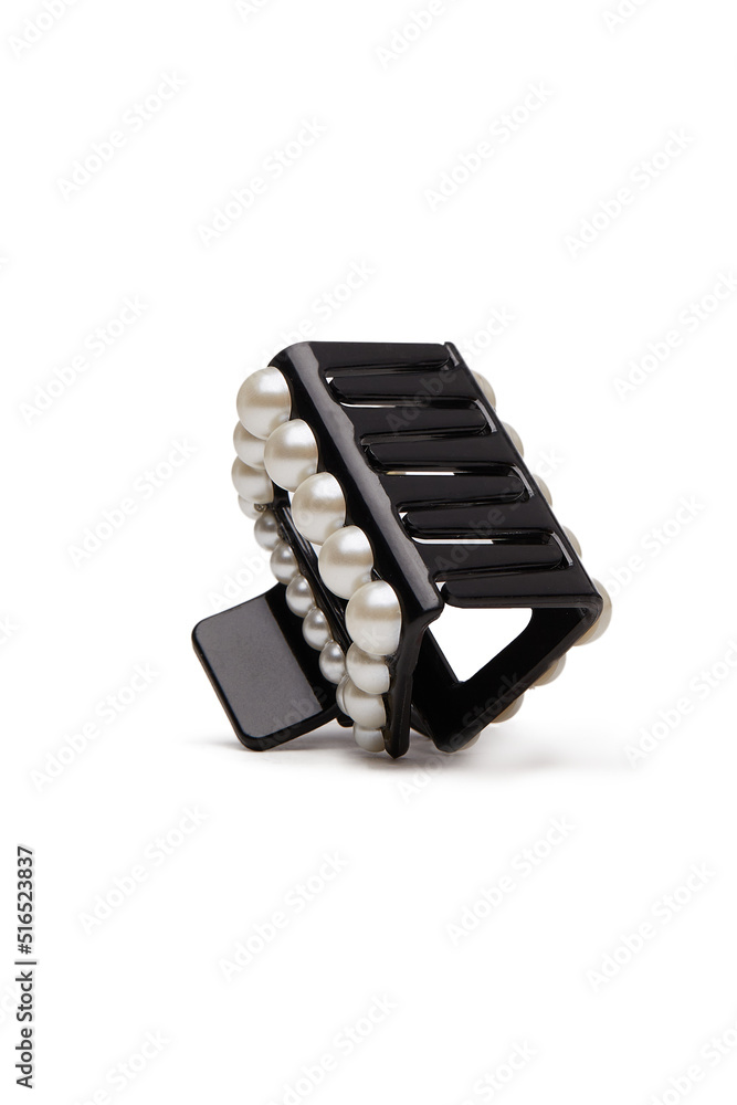 Subject shot of a black hair clip decorated with pearls. The hair clip is isolated on the white background. Vogue accessory for ladies and girls. Subject shot of a black hair clip decorated with pearls. The hair clip is isolated on the white background. Vogue accessory for ladies and girls.