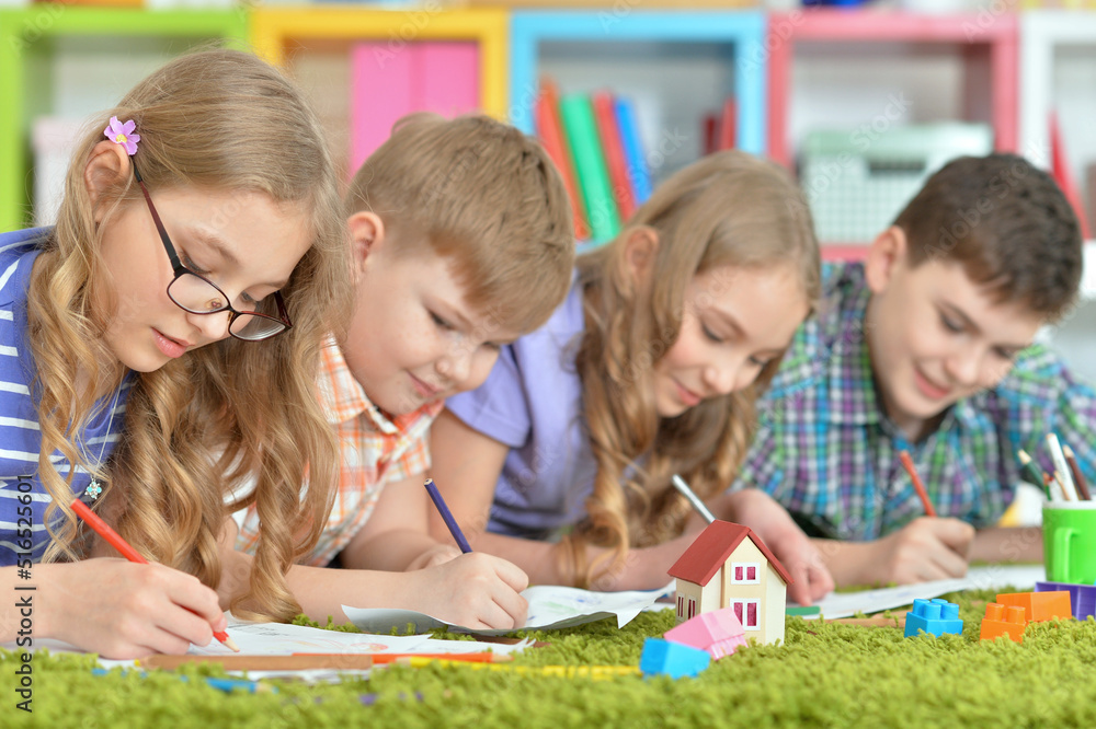 Fototapeta premium Children lying on floor drawing with pencils