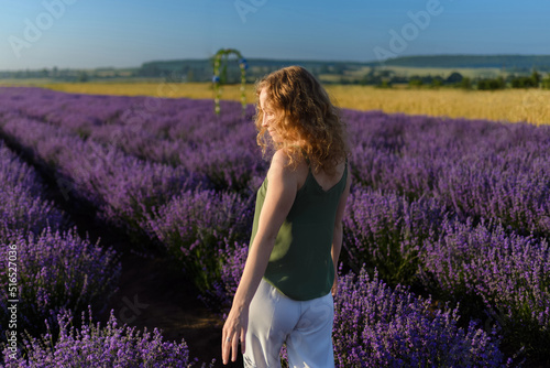 Fototapeta Naklejka Na Ścianę i Meble -  A woman walking through the lavender field, rear view