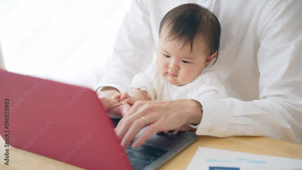 赤ちゃんを抱っこしながら自宅で仕事する男性 赤ちゃんを抱っこしながら自宅で仕事する男性
