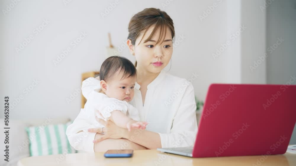 赤ちゃんを抱っこしながら自宅で仕事する女性　子育てしながらの在宅勤務
