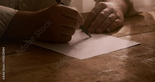 a man writes a letter on a paper on a table. Close up photo