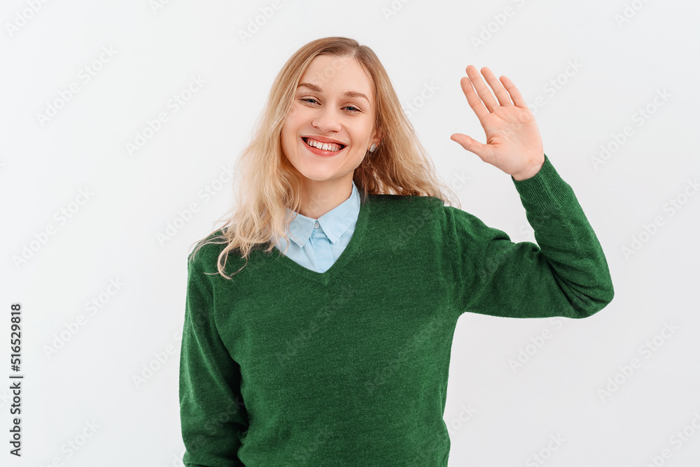 Friendly cheerful blonde girl smiling, saying hi and waving hand to greet person, make hello gesture, welcome someone, wears casual clothes. Indoor studio shot on white background Friendly cheerful blonde girl smiling, saying hi and waving hand to greet person, make hello gesture, welcome someone, wears casual clothes. Indoor studio shot on white background