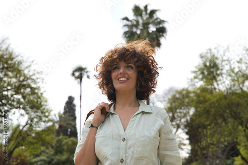 Portrait of mature and attractive woman  with curly brown hair  with brown leather jacket on shoulder and shirt  successful  empowered  happy and independent. Concept happiness  hairstyle  curls.