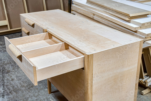 Chest of drawers made of solid alder with open drawer in process of production at workshop. Creation of modern domestic furniture for bedroom interior