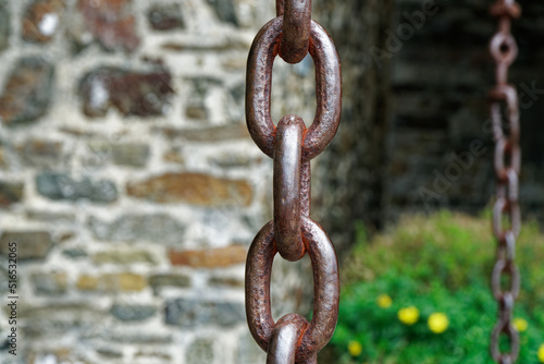 Detail einer massiven Eisenkette vor einer Bruchsteinmauer © Pixelheld