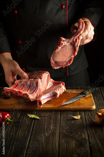 Chef holding a piece of raw meat with a bone. Pork ribs in the butcher hands. Asian cuisine