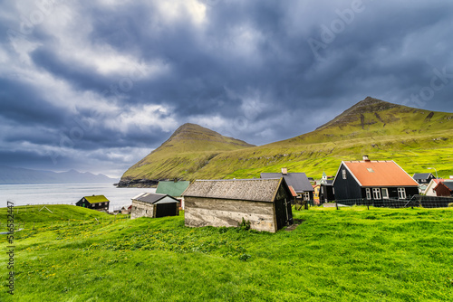 Colorful houses of Gjogv village and a small river flows into fjord. Faroe Islands, Denmark