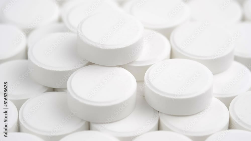Many white medical pills rotating close up. Pharmaceutical Industry and medicine concept. Many white medical pills rotating close up. Pharmaceutical Industry and medicine concept.