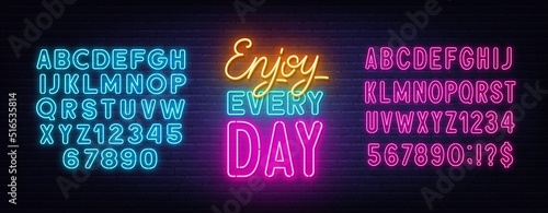 Enjoy Every day neon quote on brick wall background.