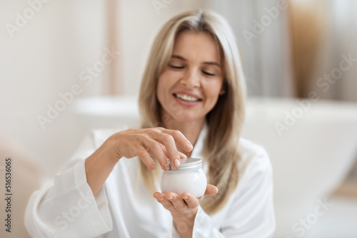 Excited blonde woman opening brand new luxury facial cream