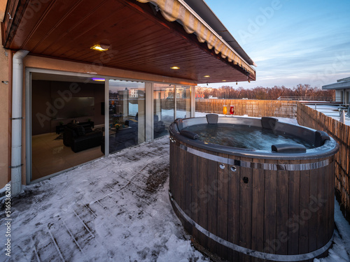 Open terrace with hot outdoor wooden bath tub. Luxury private house.