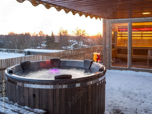 Hot outdoor wooden bath tub on terrace of private house. Finnish sauna