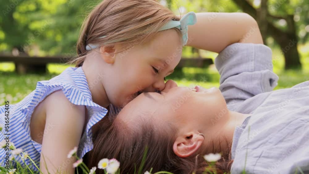 family, motherhood and people concept - happy smiling mother with baby girl lying on grass in park family, motherhood and people concept - happy smiling mother with baby girl lying on grass in park