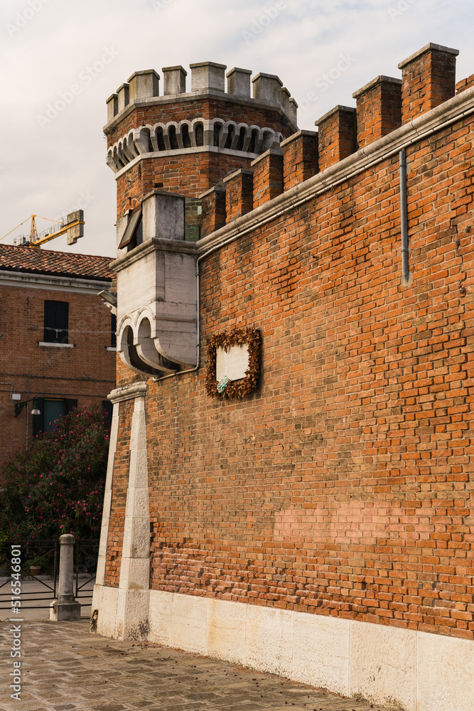 Naklejka premium Architectural detail of a red brick wall and watch tower of an old prison in Venice, Italy.