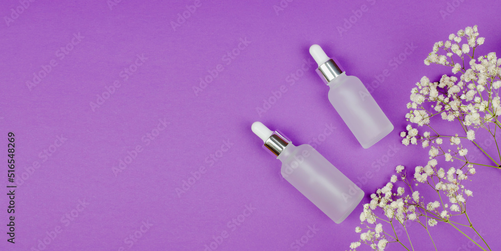 Two white bottles with skin care products on a purple background with gypsophila flowers. Skin aging problem Two white bottles with skin care products on a purple background with gypsophila flowers. Skin aging problem