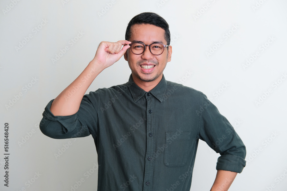 Adult Asian man smiling confident with hand touching his glasses frame Adult Asian man smiling confident with hand touching his glasses frame