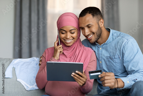 E-Commerce Concept. Pregnant Muslim Spouses Using Digital Tablet And Credit Card