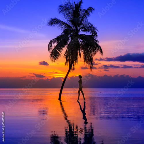 Sunset on Maldives island, luxury water villas resort, pool and palm tree. Beautiful sky and beach with palms landscape. Summer vacation and travel concept. Woman silhouette on the sunset background