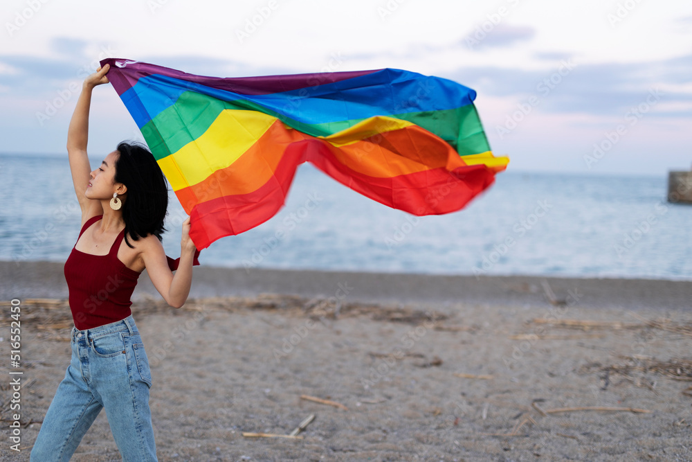 Young girl with a pride flag at the beach. LGBT community..