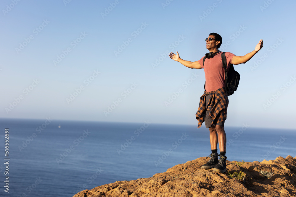 Young man standing on the stone with raised up arms. Tourist man on the top of the mountain... Young man standing on the stone with raised up arms. Tourist man on the top of the mountain...