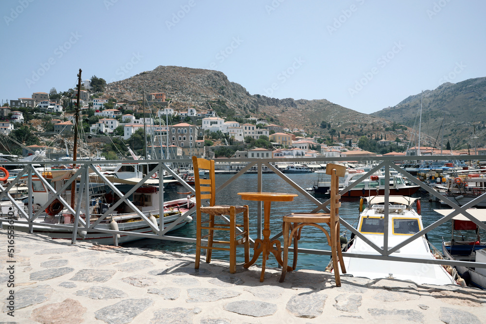 Wooden table and chairs near port with different boats on sunny day
